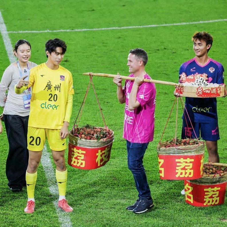Michael Owen carries lychees and cheers at Guangzhou grassroots soccer match